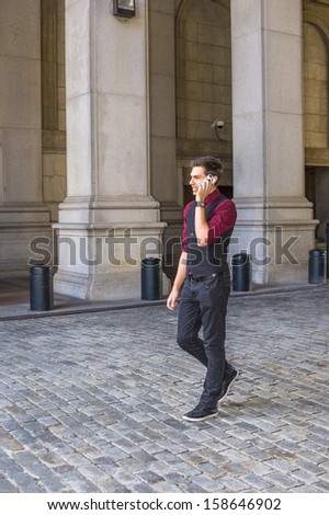 Dressing in a red shirt, a black vest, black jeans and a black tie, a young handsome guy is walking on an old fashion style street and talking on the phone / Walking and Talking