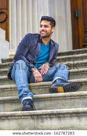 Dressing in a dark purple woolen blazer,  blue jeans and black leather shoes, a young Middle Eastern guy with bread and mustache is sitting on steps, looking around and smiling. / Big Smile