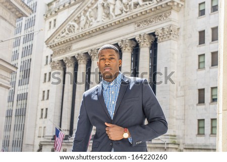 A young black businessman is standing outside an office building, confidently looking forward. / Portrait of Young Black Businessman