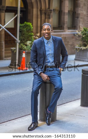 A young black businessman is sitting on the street, smiling and looking at you / Portrait of Young Black Businessman