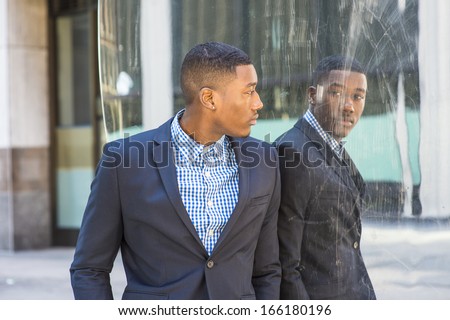A young black businessman is standing by a mirror and looking at the reflection / Looking at Mirror