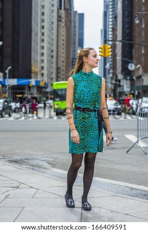 Dressing in green and black patterned sleeveless dress, black leggings, leather shoes and a black waist strap, a happy girl is standing on a busy street of a big city. / Looking for You.