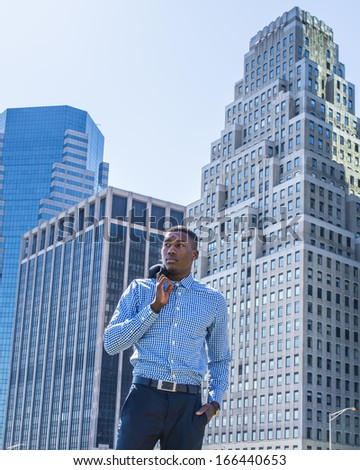 Taking off his jacket, a young black businessman is standing in the front of a busy business district, confidently looking forward. / Portrait of Young Businessman,