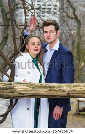 A young attractive couple is standing together and confidently looking forward in a chilling winter. / Portrait of Young Couple