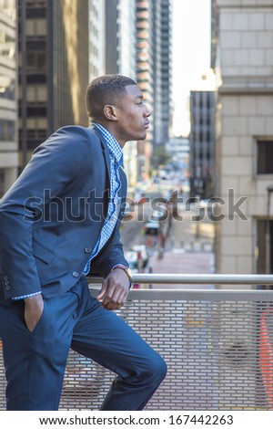 A young black businessman is standing on the balcony, looking at the street and thinking. / Looking Forward