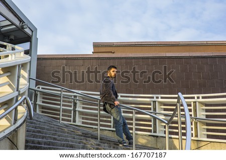 Dressing in dark purple woolen blazer and jeans, a young guy with beard and mustache is standing against a metal railing on stairs, under sunshine of sunset, thinking. / Waiting for You