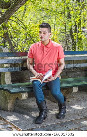 Dressing in a red Polo shirt, green pants and long leather boots, a young handsome guy is sitting on a long chair  in the morning of a spring season, reading a book. / Reading in the morning