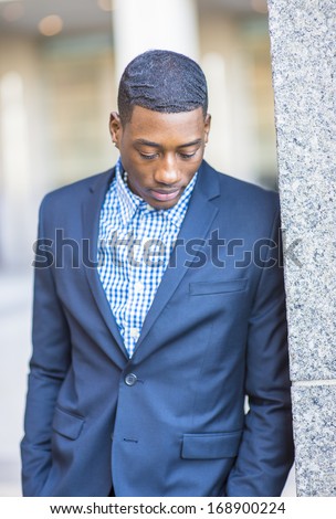 A young handsome black guy is looking down and thinking. / Thinking Outside