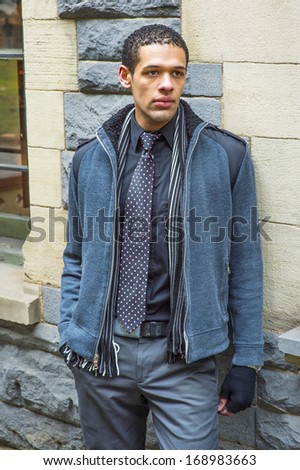 Dressing in woolen jacket with shoulder pads, tie, long scarf and gloves, a young handsome guy is standing against the wall, looking forward. /Waiting for You