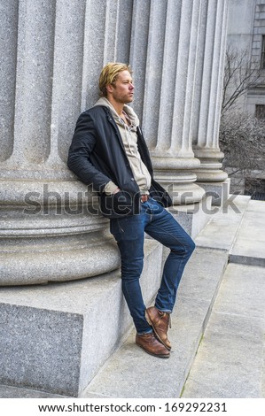 Dressing in a black jacket outside and hooded jacket inside, jeans and boots, a young handsome guy is leaning against a column, thinking. / Thinking Outside