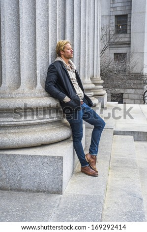 Dressing in a black jacket outside and hooded jacket inside, jeans and boots, A young handsome guy is leaning against a column outside an office building, thinking. / Thinking Outside