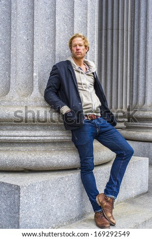 Dressing in a black jacket outside and hooded jacket inside, jeans and boots, a young handsome guy is leaning against a column outside an office building, thinking. / Thinking Outside