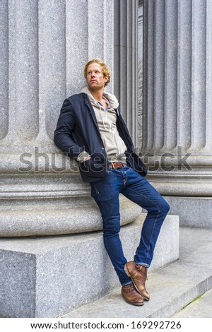 Dressing in a black jacket outside and hooded jacket inside, jeans and boots, a young handsome guy is leaning against a column outside an office building, thinking. / Thinking Outside