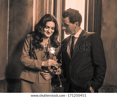 A young handsome businessman is giving a white flower to a pretty businesswoman after work. / Love Between Businessman and Businesswoman