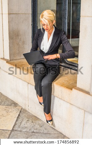 Dressing in white underclothes and a black suit, a young college student is working on a laptop computer outside by a window / Study Outside