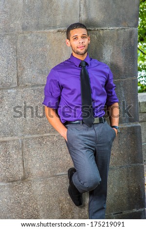 Dressing in a purple shirt, gray pants and a black tie, two hands putting in pockets, a young college student with a little beard and mustache is leaning against the wall,  thinking about you.