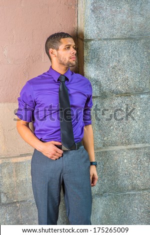 Dressing in a purple shirt, gray pants, a black tie, a young businessman with a little beard and mustache is standing in the corner,  looking forward. / Waiting for You