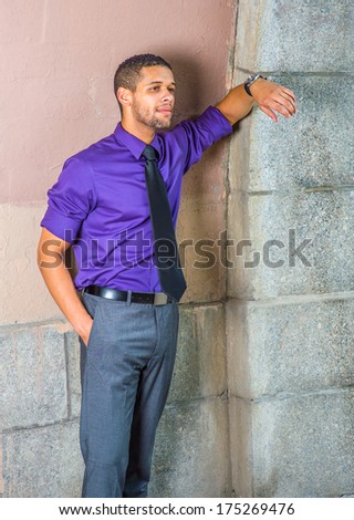 Dressing in a purple shirt, gray pants, a black tie,  one hand putting in a pocket, one arm resting on the wall, a young businessman with a little beard and mustache is standing in corner,  waiting