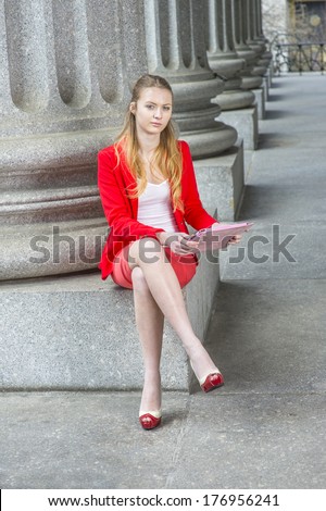 Dressing in a red blazer, white under wear, a red skirt and open toes high heels, crossing legs, a female college student is sitting by columns on campus, studying on a tablet computer.