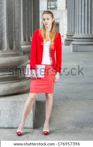 Dressing in a red blazer, white under wear, a red skirt, open toes high heels, holding a tablet computer, a female college student is standing outside an office building. /Portrait of College Student