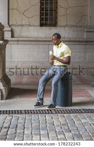 Frowned, patiently, a young black guy, dressing in a light yellow shirt, gray pants, black shoes, is holding a white rose, sitting by street in old city, waiting for you /Unhappy Guy Waiting on Street