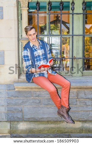 Man Reading Outside. Dressing in a blue and white pattern shirt,  a blue hood vest,  red jeans and brown leather boot shoes, a college student is sitting by a window, reading a red book.