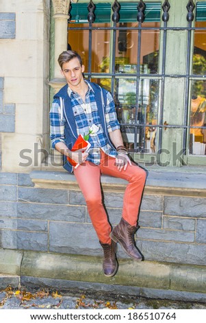 Man Waiting for You. Dressing in a pattern shirt,  a hood vest,  red jeans and brown leather boot shoes, a young guy is sitting by a window, holding a red book and a white flower, waiting for you.