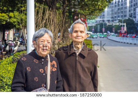Portrait of a candid senior couple enjoying their retirement. Two 80 years old man and woman are standing on a street, looking forward.