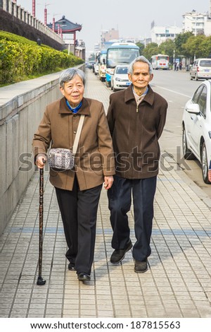 Senior Man and Woman Walking Outside. A  senior couple, 80 years old, is walking on street, woman holding a walking stick.