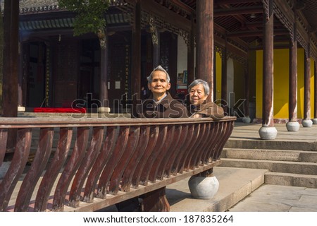 ANQING, CHINA - MARCH 22: Senior Man and Woman sit on a bench to take a break. A  senior couple, 80 years old, sit on a bench inside Yinjiang Temple on  March 22, 2014 while they visit the temple.