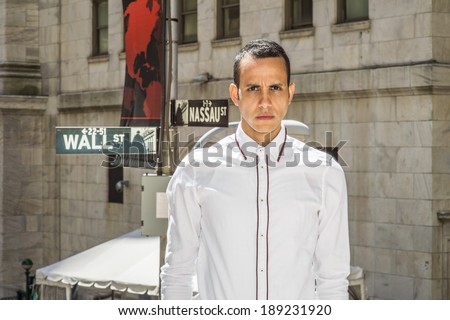 Businessman on Wall Street. Dressing in a white shirt, a young handsome man is standing on street, confidently looking forward. Wall Street sign in the background.