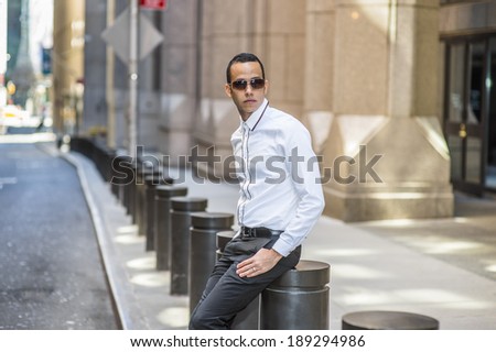 Man Waiting for You. Dressing in a white shirt, black pants, wearing sunglasses, a young, mysterious guy is sitting on the street, relaxing and waiting for you.