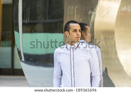 Man with Reflection. A young handsome guy is standing by a mirror wall, passionately waiting for you.