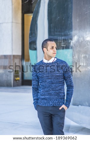 Man Casual Fashion.  Dressing in a blue patterned sweater, black pants, two hands putting in pockets, a young attractive guy is standing by a metal mirror structure, waiting for you.
