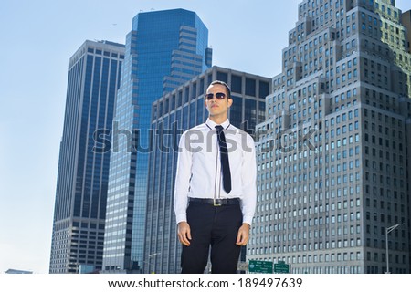 Portrait of Young Businessman. Dressing in a white shirt, a black necktie, wearing sunglasses,  a young handsome guy is standing in the front of corporation buildings, confidently looking forward.
