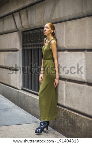 Woman Relaxing on Street. Dressing in a green, long Maxi Tank Dress,  black dress sandals, a young black lady is standing by old fashion style window and wall,  looking up, lost in thought.