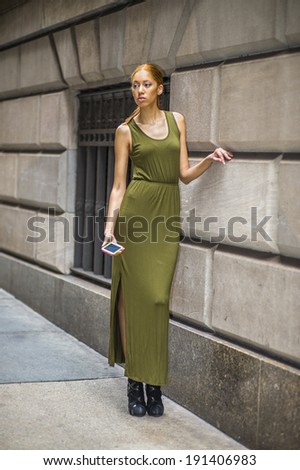 Woman waiting your call. Dressing in a green, long Maxi Tank Dress,  black dress sandals, a young black lady is standing by old fashion style window and wall,  holding a mobile phone, lost in thought.
