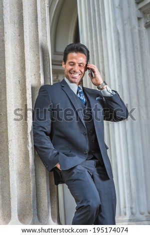 Man Calling Outside. Dressing in dark blue suit, necktie, a handsome, sexy, middle age businessman is standing outside office, smiling, making a call on cell phone.