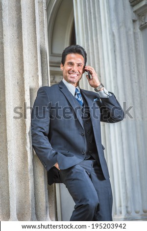 Man Calling Outside. Dressing in dark blue suit, necktie, a handsome, sexy, middle age businessman is standing outside office, smiling, making a call on cell phone.