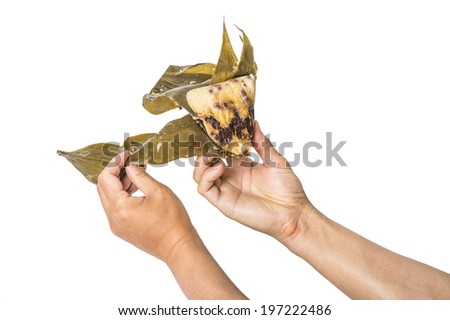 Traditional Chinese rice pudding with red bean and date, wrapped with bamboo leaf, hands holding and peeling, isolated on white background.