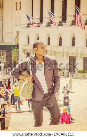 Man Traveling. Carrying a bag, walking up on steps, a young black college student is standing in the front of an office building, confidently looking forward.