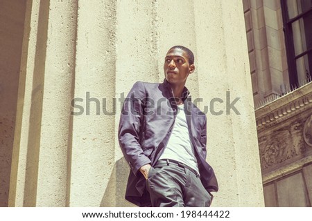 Young black man thinking outside. Wearing a white under wear, fashionable jacket, two hands in pockets, a young black college student is standing under strong sun light, looking around, thinking.