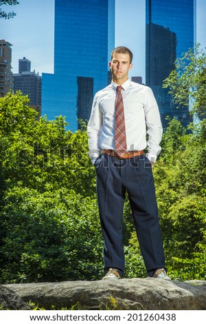 Portrait of Young Businessman. Wearing a white long sleeve shirt, black pants, a pattern tie, hands in pockets, young professional guy is standing in the front of business district, looking forward.