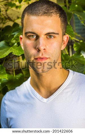 Portrait of young man, wearing a white V neck T shirt,  short hair.
