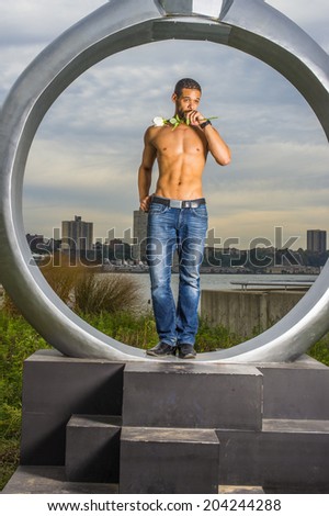 Man Waiting for You. Holding a white rose, covering his mouth, a sexy, muscular guy, half naked, is standing on a big ring, looking forward, waiting for you.