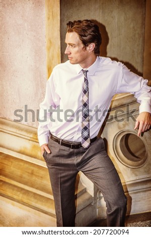 Businessman Waiting for You. Dressing in a white shirt, patterned neck tie,  gray pants, a young businessman is standing by a railing, looking away, relaxing.