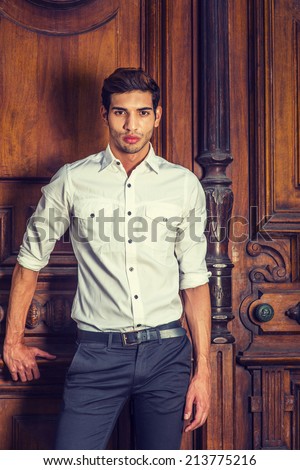 Portrait of Young Businessman. Wearing a white shirt, black pants, a young college student is standing by an old fashion style office door, seriously into deeply thinking.