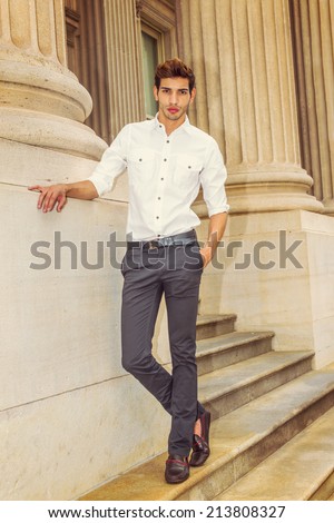 Portrait of Young Businessman. Wearing a white shirt, black pants, leather shoes, a young college student is standing outside an office building, confidently looking at you.