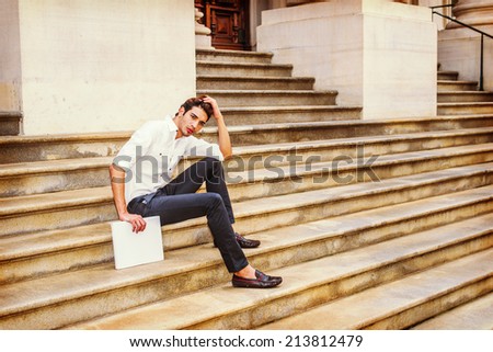 College Student. Wearing white shirt, black pants, leather shoes, holding a white book, hands scratching head, a young handsome guy is sitting on stairs outside an office building, relaxing, thinking.