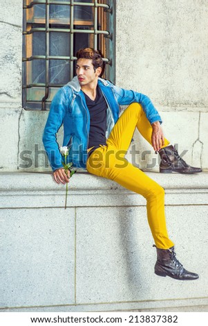 Man Waiting for You. Dressing in a blue jacket with hood, black under wear, yellow pants, leather boot shoes, a young handsome guy is sitting by a window, holding a white rose, looking around.